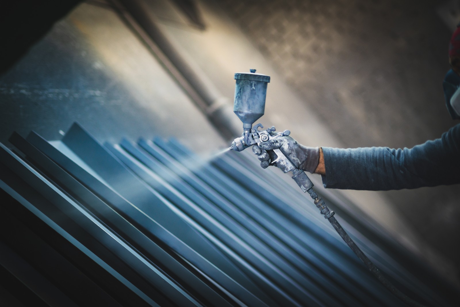 Man painting metal products with a spray gun