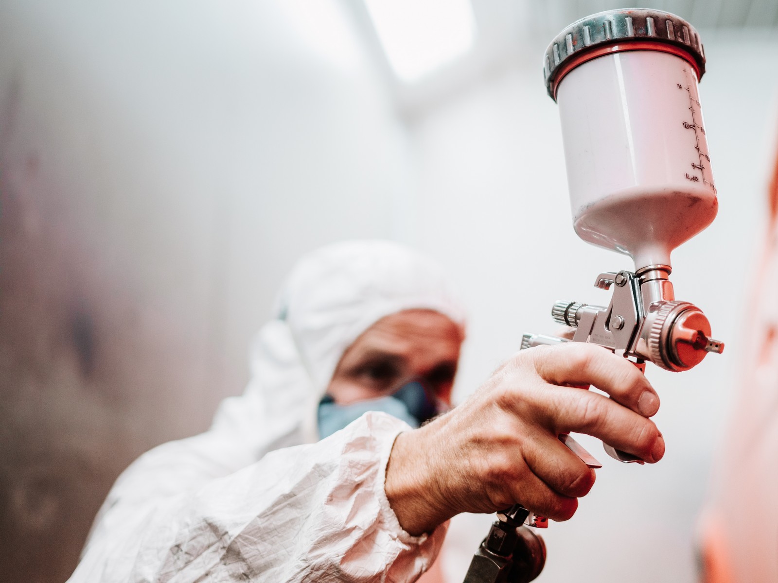 close up of paint spray gun, worker painting a car